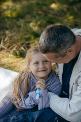 Adult father and little daughter are walking in the park
