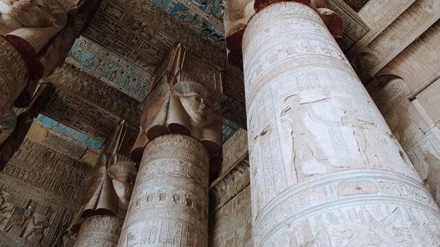 Colonnade at Hypostyle Hall of Temple of Hathor. Columns are decorated with reliefs and hieroglyphics. Dendera Temple complex, Qena, Egypt. Handheld real time footage