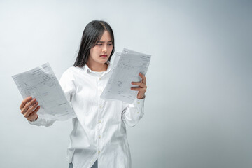 A stressed and anxious young woman expresses shock and despair while reviewing numerous overdue bills and financial statements. Concept for business, finance, advertising, and lifestyle topics.