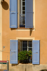 charming building facade with a warm peach-colored wall and two windows.features blue wooden shutters