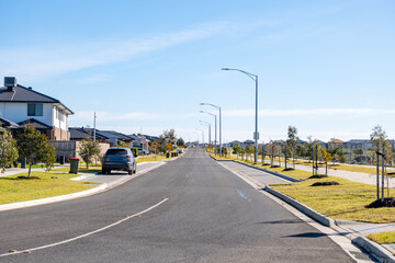 Wide residential street in Wyndham Vale, outer suburb of Melbourne, Australia, with new houses, young trees, modern infrastructure. Concept of suburban development, community living, urban planning