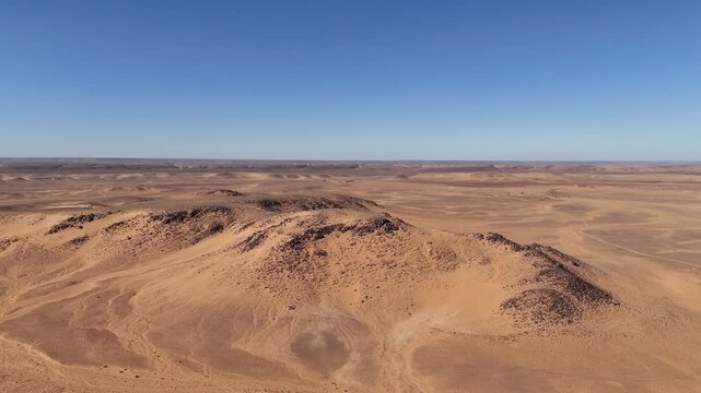Drone aerial view of the Eye of the Sahara in Mauritania, an iconic natural wonder with striking circular patterns in the vast desert landscape against blue sky