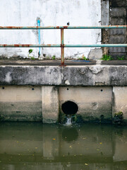 Polluted urban canal with sewage discharge pipe and contaminated water - Environmental pollution...