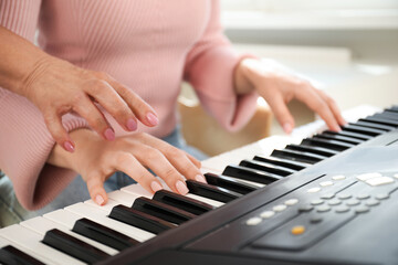 Fototapeta premium Tutor teaching woman to play piano indoors, closeup