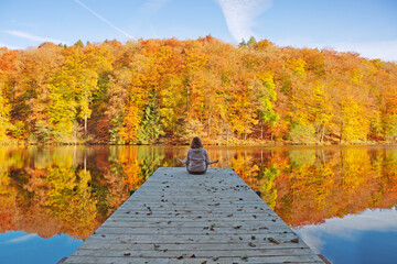 Woman meditating outdoors in the autumn park near forest lake.