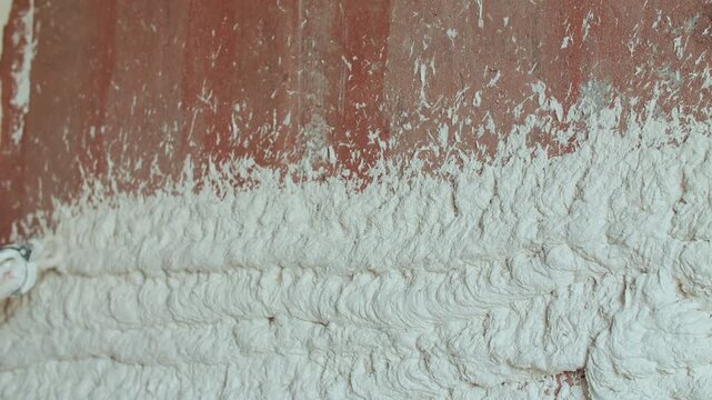 Plaster Being Sprayed onto Brick Wall During Construction