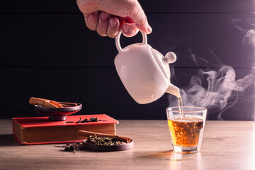 Hot tea is poured into glasses with steam. Teacups are placed on the table in the warm atmosphere of morning sunlight.