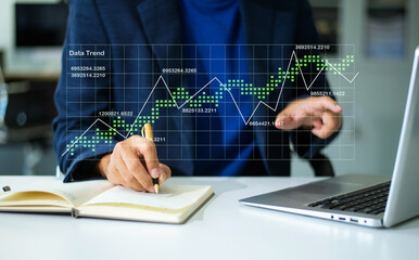 Hand using a stylus on tablet with digital trend graph overlay and laptop. Ideal for fintech, analytics, report, chart,	
