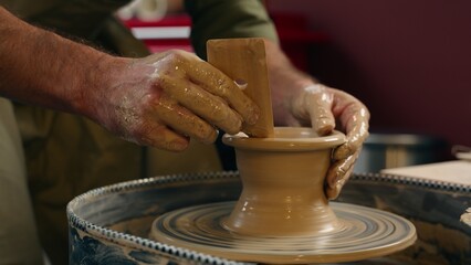 Close up smiling happy focused Caucasian man guy small business owner businessman crock potter male making pottery ceramic shaping wet clay rotating wheel looking at camera wave hand indoors workshop