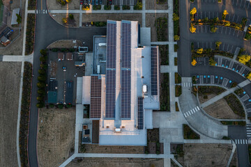 Aerial drone picture of a modern college building in Oregon City with rooftop solar panels, showcasing renewable energy technology and sustainable architecture in an academic campus setting