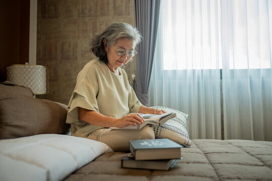 Elderly woman reading book appears calm and relaxed, enjoying a peaceful related to aging gracefully, relaxation, knowledge, retirement lifestyle, wellness, and peaceful living at home.
