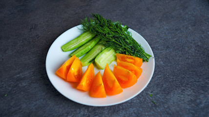 Fresh vegetable salad with cucumbers, tomatoes, and purple lettuce leaves served on a white plate. Healthy vegetarian food
