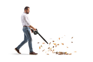 Full length profile shot of a man blowing dry autumn leaves with a leaf blower