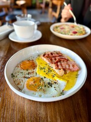 Fried eggs with toast and bacon served on plate