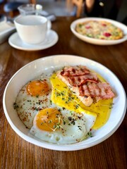 Fried eggs with toast and bacon served on plate