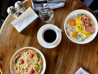 Breakfast table with coffee, eggs, bacon, and omelet