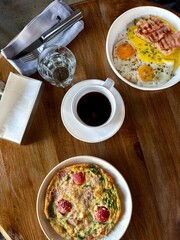Breakfast table with coffee, eggs, bacon, and omelet