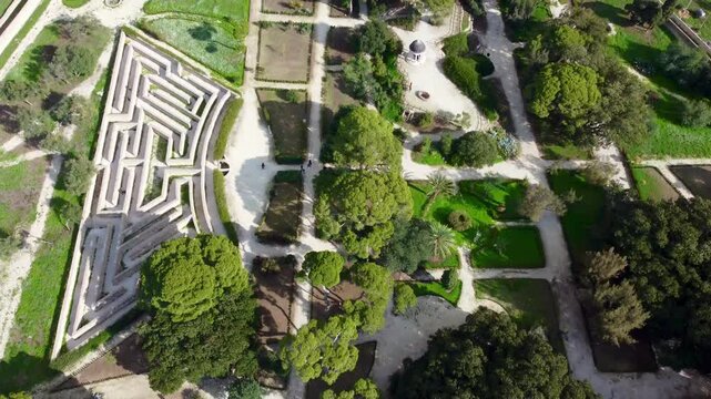 Aerial 4k drone footage of Donnafugata Castle in Sicily, Italy, showing the historic Baroque-style castle, surrounding gardens, rolling hills, and scenic Sicilian countryside under clear skies.
