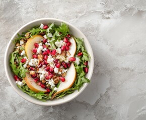 Vegan salad bowl with arugula, pear, pomegranate, coconut crumble or cottage cheese on marble tabletop.