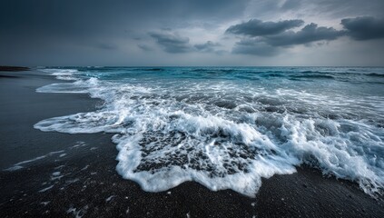 Dark beach, foamy waves, stormy sky.  Ocean meets shore, dramatic clouds