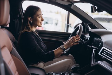 Woman buying new car in auto showroom