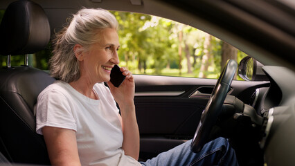 Happy smiling laughing Caucasian mature senior glad woman female pensioner auto car driver talking mobile phone chatting smartphone call opening automobile door leaving transport vehicle outside park
