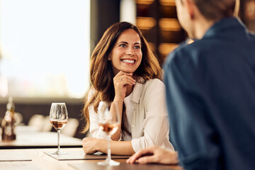Smiling Young Woman Enjoying a Conversation Over Drinks in a Relaxed Cafe Setting
