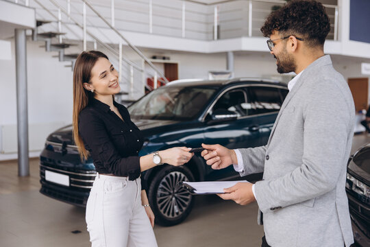 Woman buying new car in dealership receiving car keys