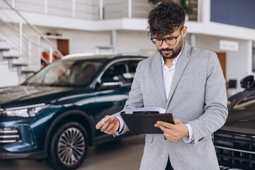 Arab man checking paperwork in car dealership