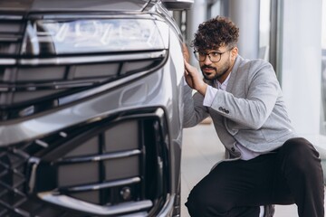 Arab man examining new car in dealership showroom