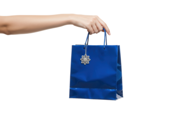 Isolated hand holding a shiny blue gift bag with an ornamental snowflake charm attached