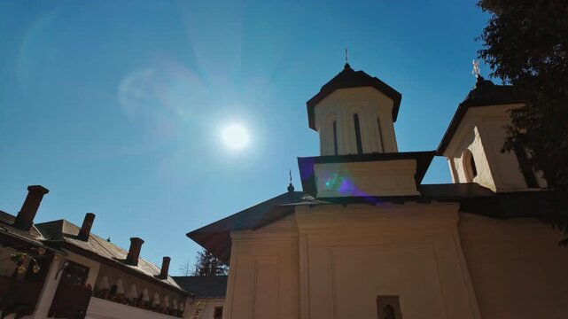 Exterior of the Sinaia Orthodox Monastery, Sinaia, Transylvania, Romania, presenting arched porticos within tranquil monastic grounds and landscaped paths