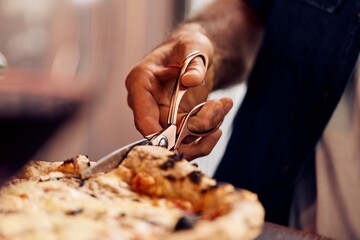 Close-Up of Hand Cutting Pizza with Scissors in a Serving Scene