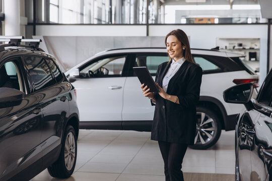 Woman car saleswoman using tablet in dealership showroom