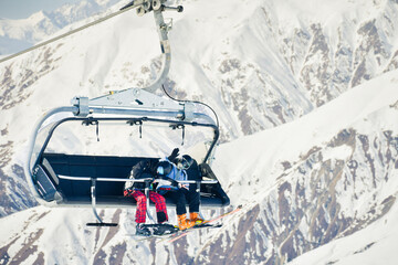 Two skiers sitting on chairlift above snowy alpine landscape, concept of winter holiday, ski resort transport, lifestyle and adventure tourism © Evaldas