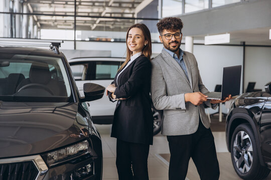 Diverse sales team posing in modern car dealership