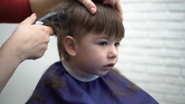 three-year-old sitting in barber chair watching