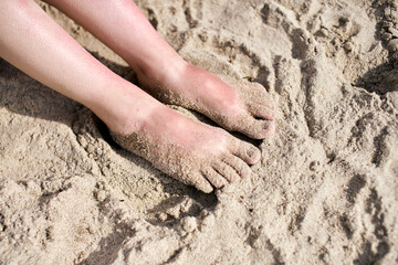Bare feet on sunlit sandy beach
