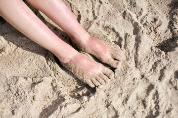 Bare feet on sunlit sandy beach