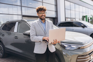 Arab man using laptop at car dealership