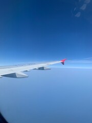 Fototapeta premium Stunning photo of airplane wing, clouds, and snowy mountains from above. Perfect for travel blogs, aviation themes, and winter adventure designs.