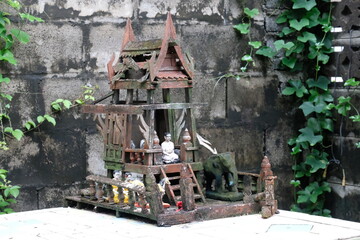 An Ancient, Weather-Worn Thai Spirit Shrine Standing in Humble, Fading Grandeur