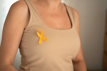 Close-up of yellow satin awareness ribbon on clothing, representing compassion and solidarity with...