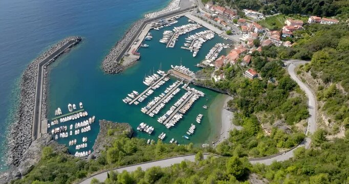 Aerial view of the marina of Maratea, in the province of Potenza, Basilicata, Italy. It is a small port overlooking the blue waters of the Mediterranean Sea, nestled between green mountains.