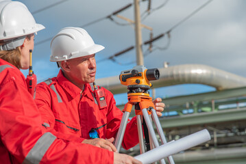 Construction workers or engineer examine blueprints outdoors and using surveying equipment