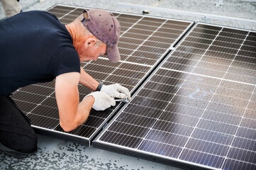Worker building photovoltaic solar panel system on rooftop of house. Close up of man engineer in...