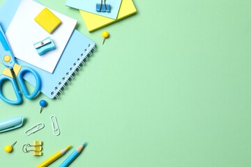 School supplies including notebook, pencils and stationery on green background