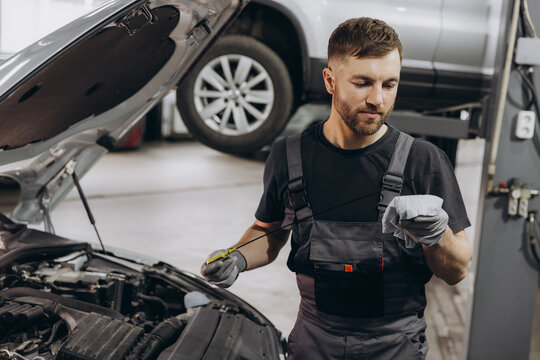 Auto mechanic checking car engine oil level