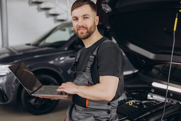 Auto mechanic using laptop for car diagnostic in service