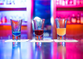 Colorful cocktails in shot glasses on bar counter